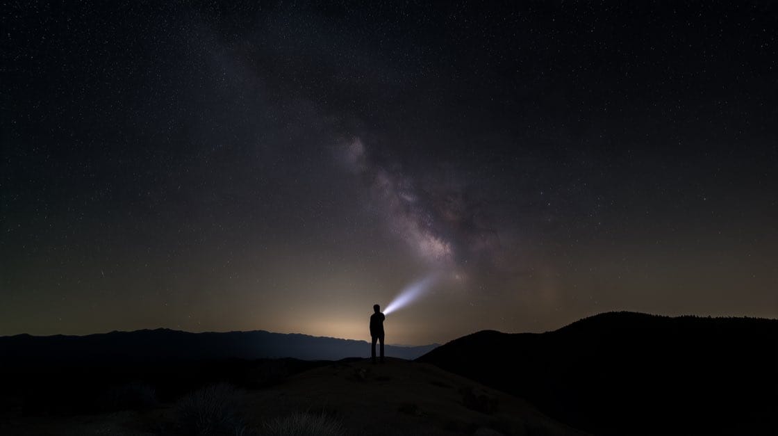A hiker under the Milky Way on a dark ridge